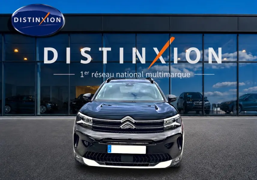 Vue avant d'un Citroën C5 Aircross noir 2025 avec calandre distinctive et phares LED, devant un showroom Distinxion.