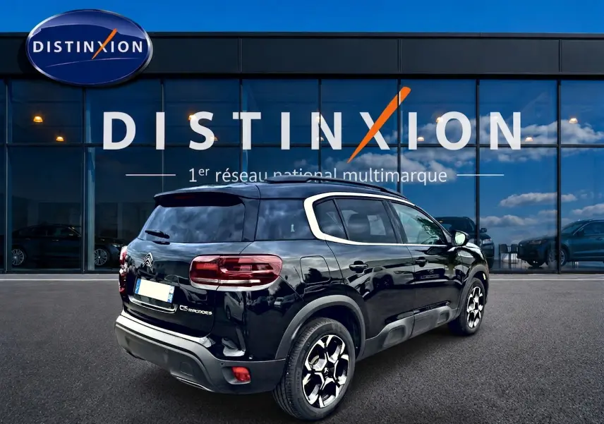 Vue 3/4 arrière droite d’un Citroën C5 Aircross noir avec jantes alu et vitres arrière teintées devant un showroom Distinxion.