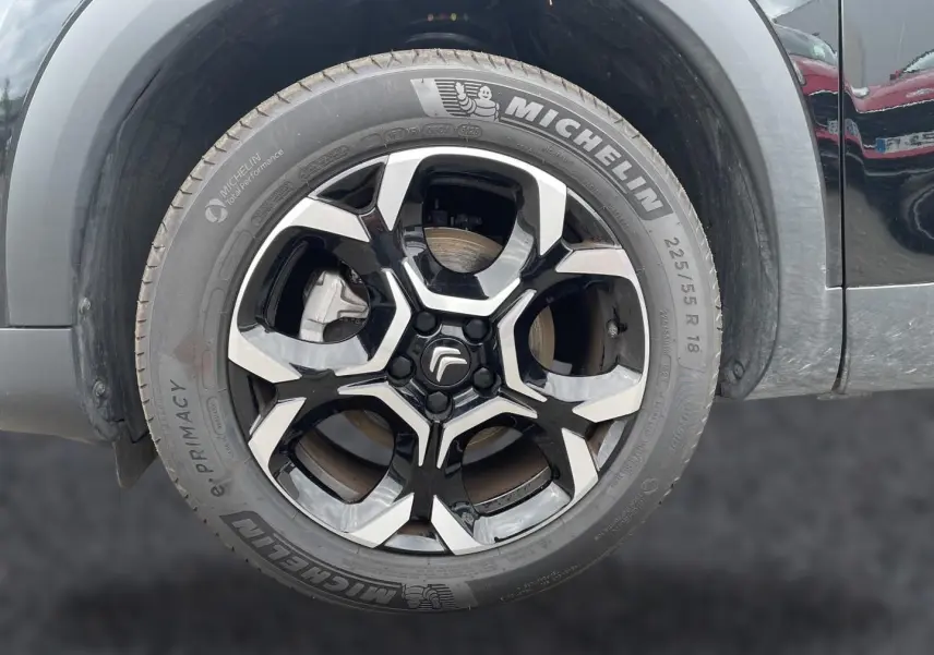 Gros plan sur la jante alu noire et argentée avec logo Citroën d’un Citroën C5 Aircross noir, vue côté avant droit.