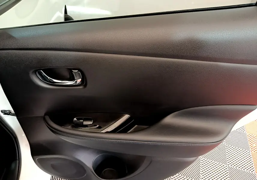 Porte intérieure côté gauche noire de Nissan Leaf blanche 2020, avec poignée chromée et commande de vitre.