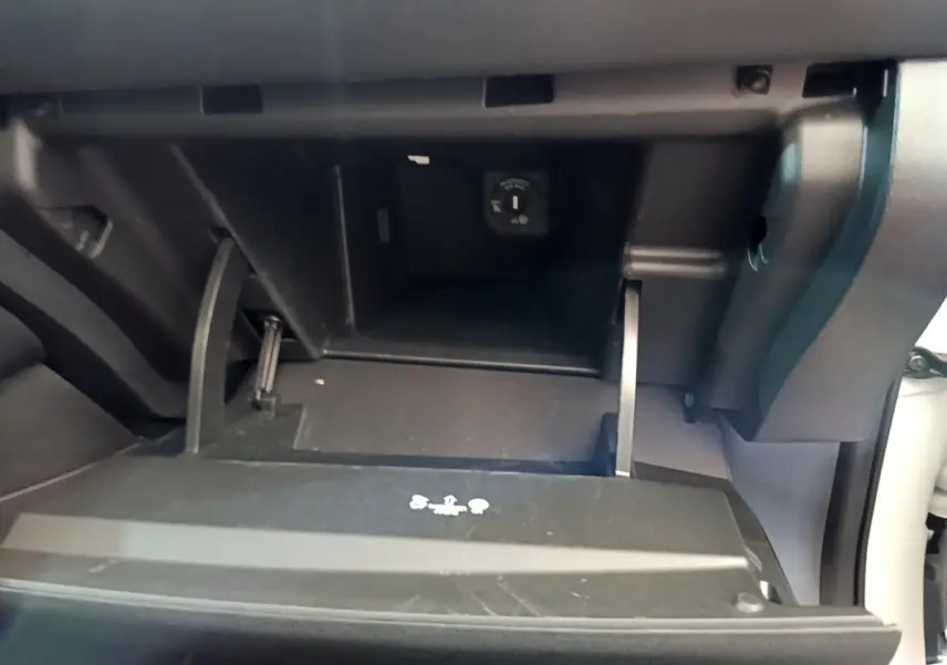 Vue rapprochée de la boîte à gants ouverte du Nissan Leaf blanc 62 kWh 217ch Business+ avec prise 12V visible.