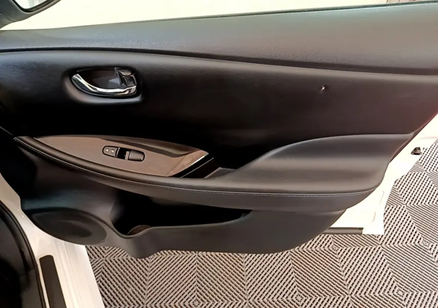 Gros plan sur la porte côté conducteur noire avec commandes électriques sur une Nissan Leaf blanche de 2020.