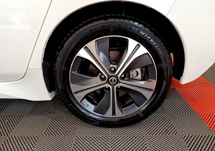 Gros plan sur la roue avant droite avec jante alliage bicolore d'une Nissan Leaf blanche 2020 électrique.