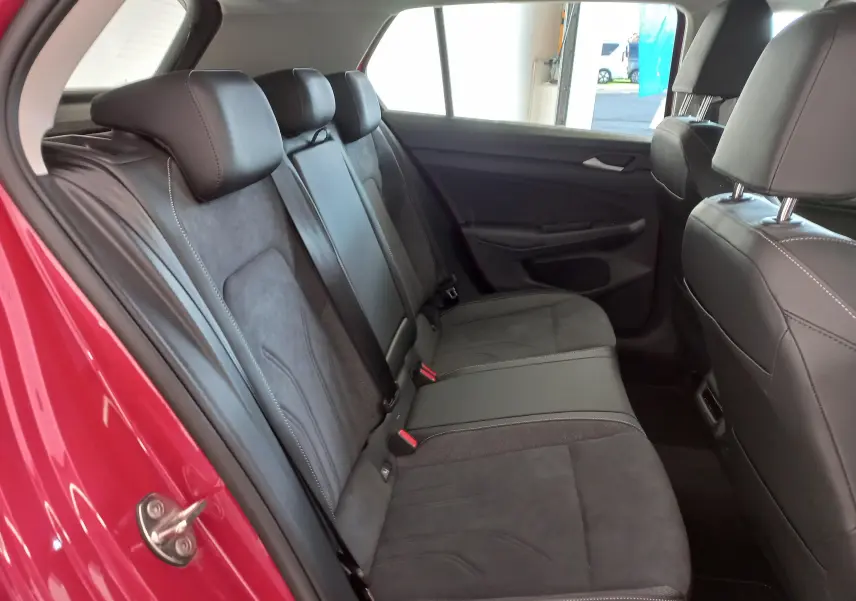 Vue intérieure du siège arrière côté gauche d'une Volkswagen Golf 2.0 TDI 150 DSG7 Style rouge Roi avec sellerie noire en cuir et alcantara.