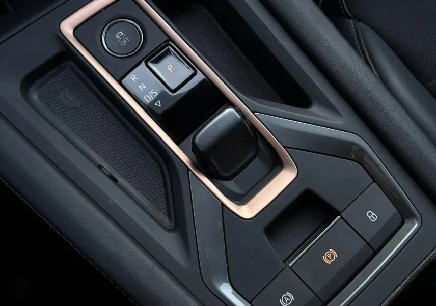 Gros plan sur la console centrale noire et cuivre avec commandes de boîte auto et frein à main électrique de la CUPRA Leon 2025.