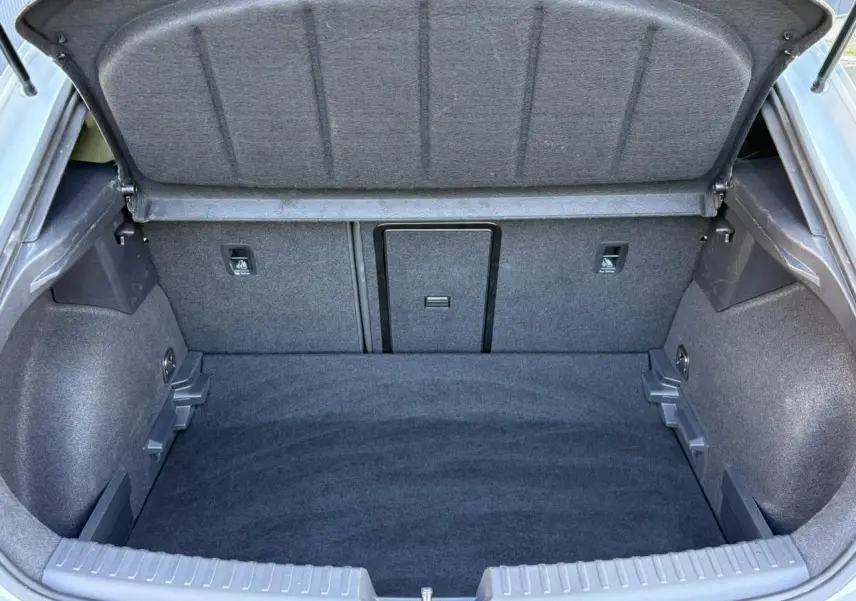 Vue intérieure du coffre ouvert de la CUPRA Leon 2025, montrant un espace de rangement propre et tapissé en tissu gris.