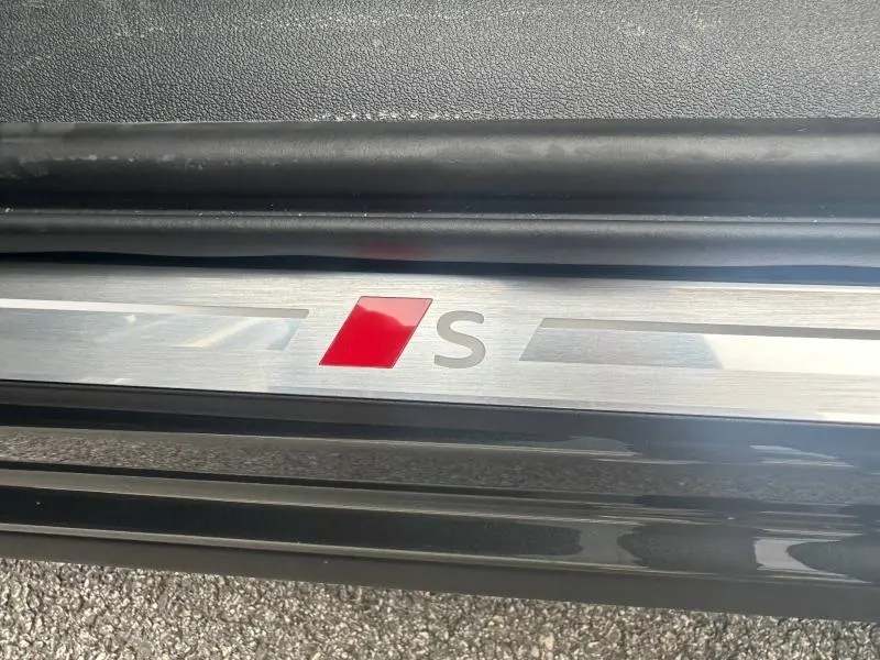 Gros plan sur la plaque de seuil de porte avec logo S rouge et gris sur Audi Q3 gris 2026 finition S line.