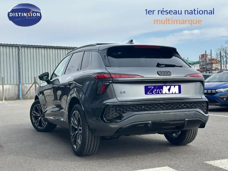 Audi Q3 gris 3/4 arrière droit, version 2.0 TDI S line 2026 avec feux arrière étirés et jantes sport.