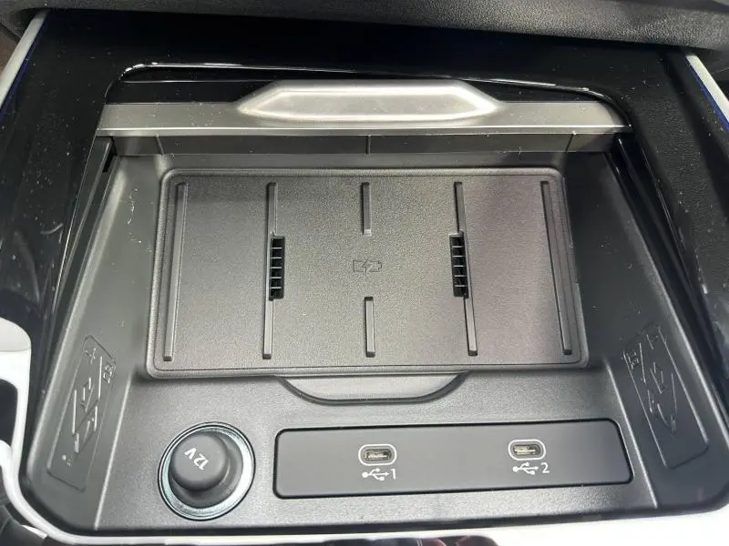 Gros plan intérieur sur la console centrale de l'Audi Q3 2026 gris, montrant un chargeur sans fil et deux ports USB-C.