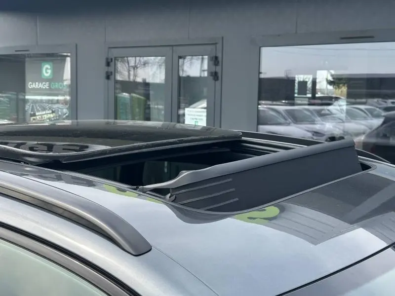 Toit ouvrant partiellement ouvert sur le dessus d’un Audi Q3 gris 2026, vue rapprochée en extérieur.