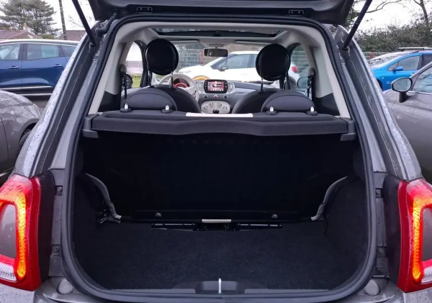 Coffre ouvert vu de l'arrière d'une Fiat 500 gris Electroclash, intérieur noir avec tableau de bord visible.