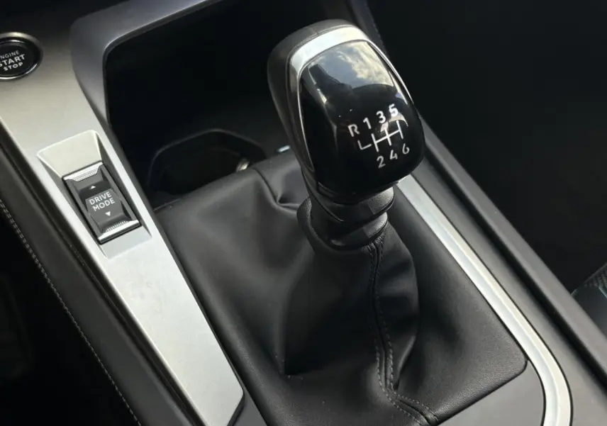 Gros plan sur levier de vitesses manuel noir et bouton Drive Mode dans l’habitacle d’une Peugeot 308 2024.