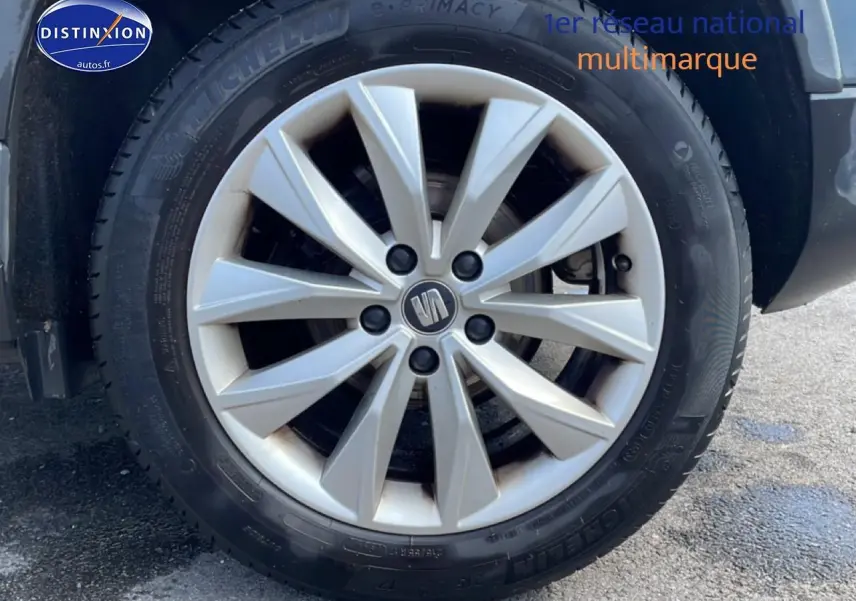 Gros plan sur la roue avant droite du SEAT Ateca bleu/gris avec jante alliage et logo central visible.