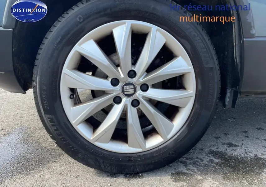 Gros plan sur la roue avant gauche du SEAT Ateca bleu/gris avec jante alliage et logo central Seat visible.