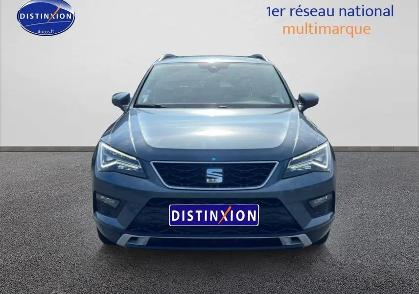 Vue frontale d'un SEAT Ateca bleu/gris 2019 avec calandre noire et phares LED allumés sur fond neutre.