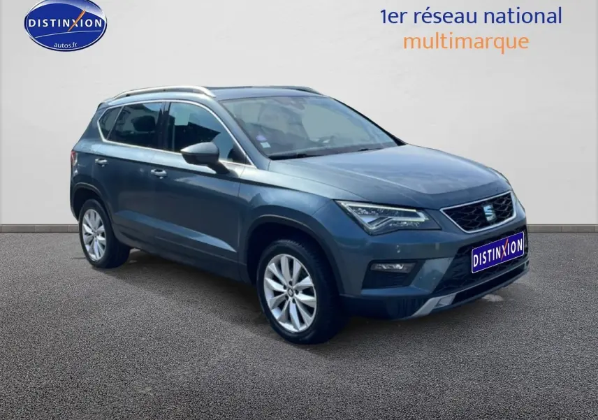 SEAT Ateca bleu/gris en 3/4 avant droit, avec jantes alu et barres de toit visibles sur fond neutre.