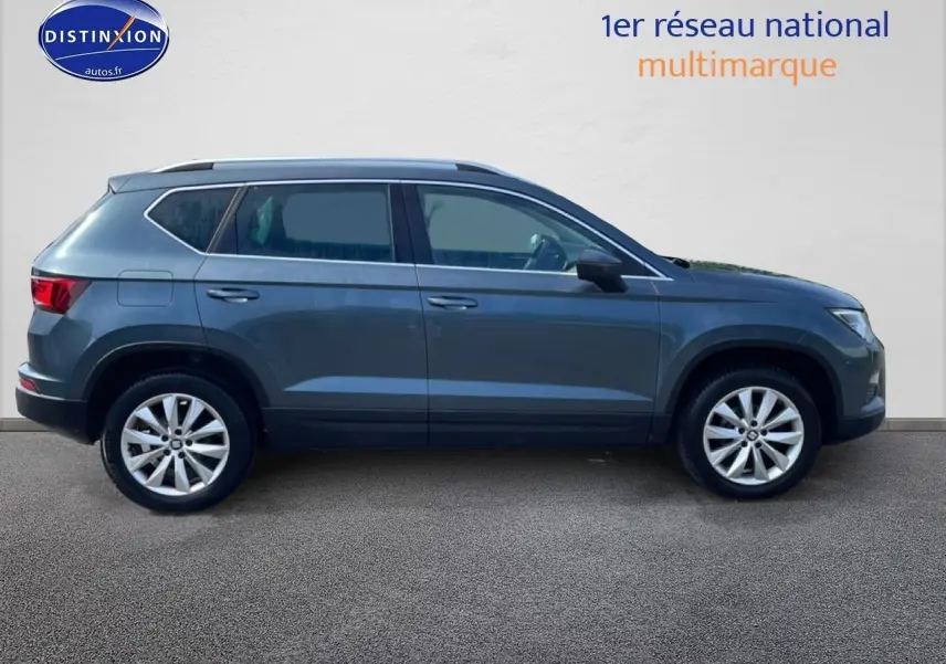 Vue latérale droite d'un SEAT Ateca 2019 bleu/gris avec jantes alu et barres de toit, sur fond neutre.