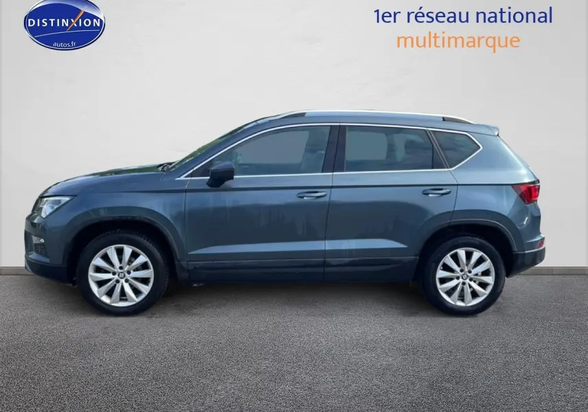 Vue de profil côté gauche d'un SEAT Ateca bleu/gris 2019 avec jantes alliage et barres de toit.
