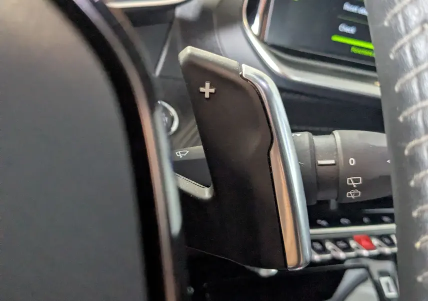 Gros plan sur la palette de changement de vitesse droite avec symbole plus, intérieur noir du Peugeot 2008 bleu 2022.