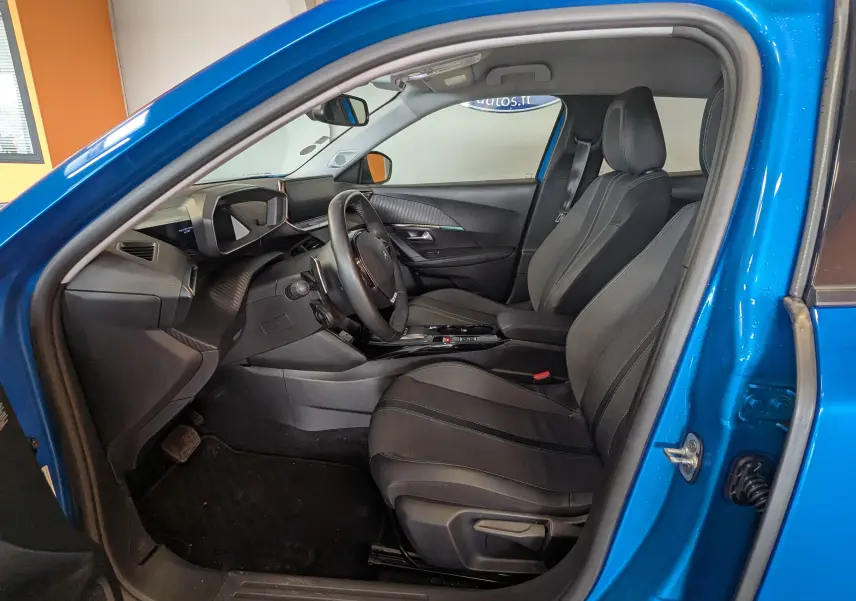 Vue intérieure côté conducteur de la Peugeot 2008 bleu 2022, montrant sièges noirs et tableau de bord moderne.