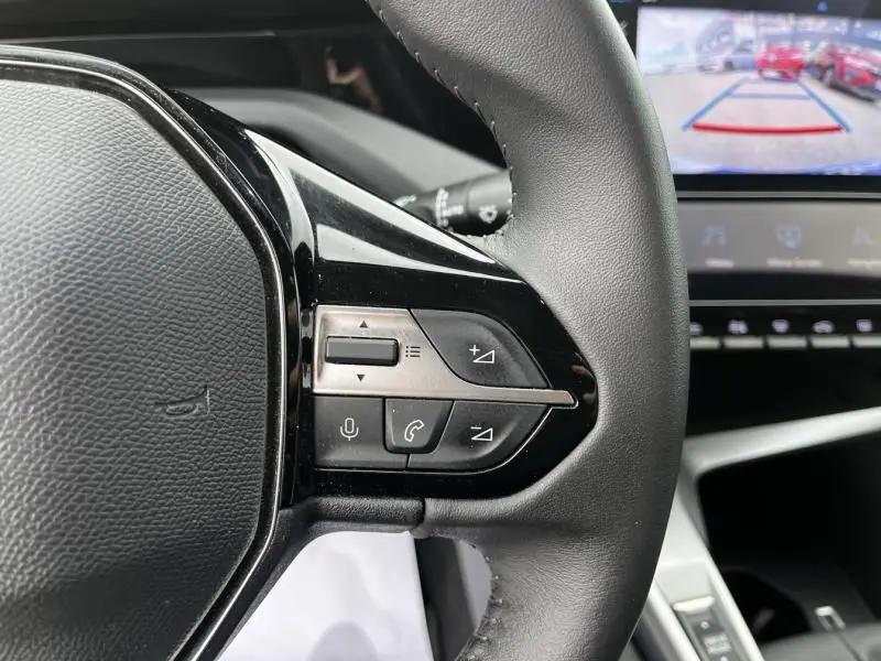 Gros plan sur les commandes au volant droit de la Peugeot 308 1.2 PureTech 130 Allure 2023, intérieur moderne avec écran tactile.