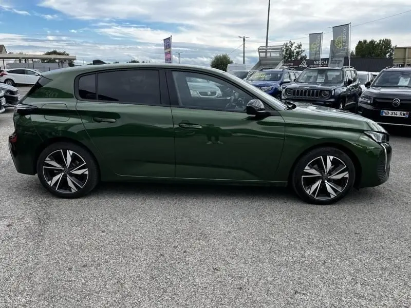 Vue latérale côté droit d'une Peugeot 308 1.2 PureTech 130 Allure 2023 en vert olivine avec jantes alliage distinctives.
