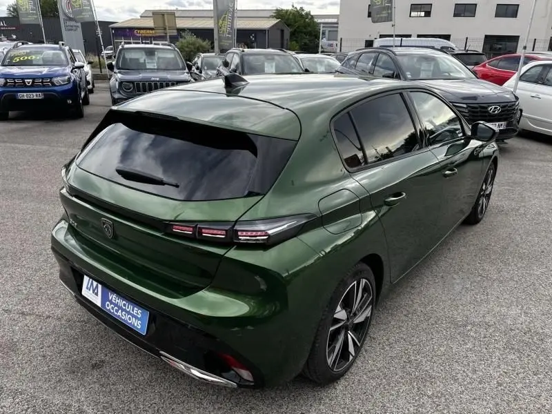 Vue 3/4 arrière droite d'une Peugeot 308 1.2 PureTech 130 Allure 2023 en vert olivine avec vitres teintées et feux LED distinctifs.