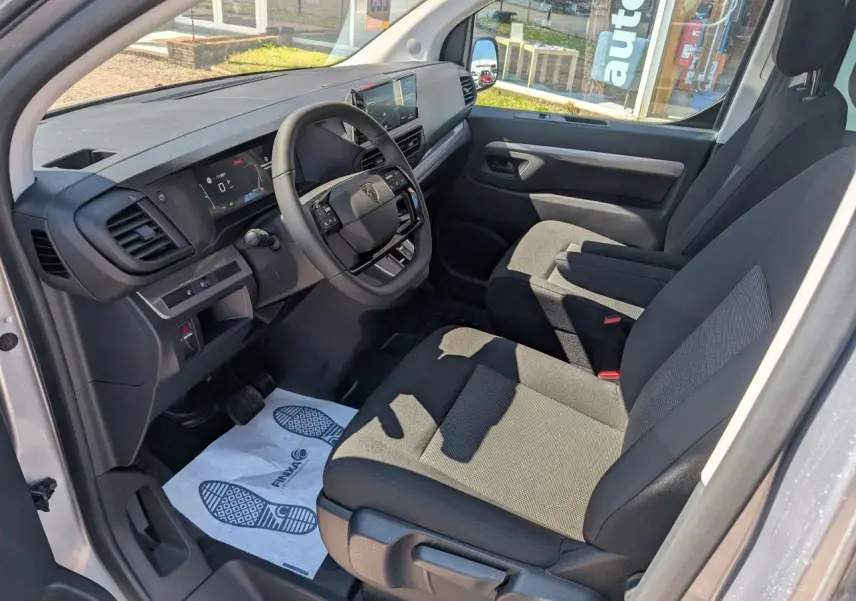 Vue intérieure côté conducteur du Peugeot Expert Fourgon XL 2026, montrant sièges tissu bi-ton gris et tableau de bord numérique.