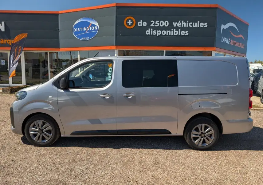 Profil côté gauche d'un Peugeot Expert Fourgon gris métallisé avec jantes alliage 17'' devant un concessionnaire.
