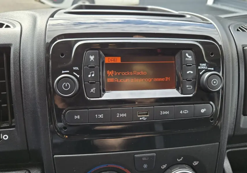 Gros plan sur la console centrale noire du tableau de bord du Fiat Ducato Fourgon avec écran radio et commandes audio.