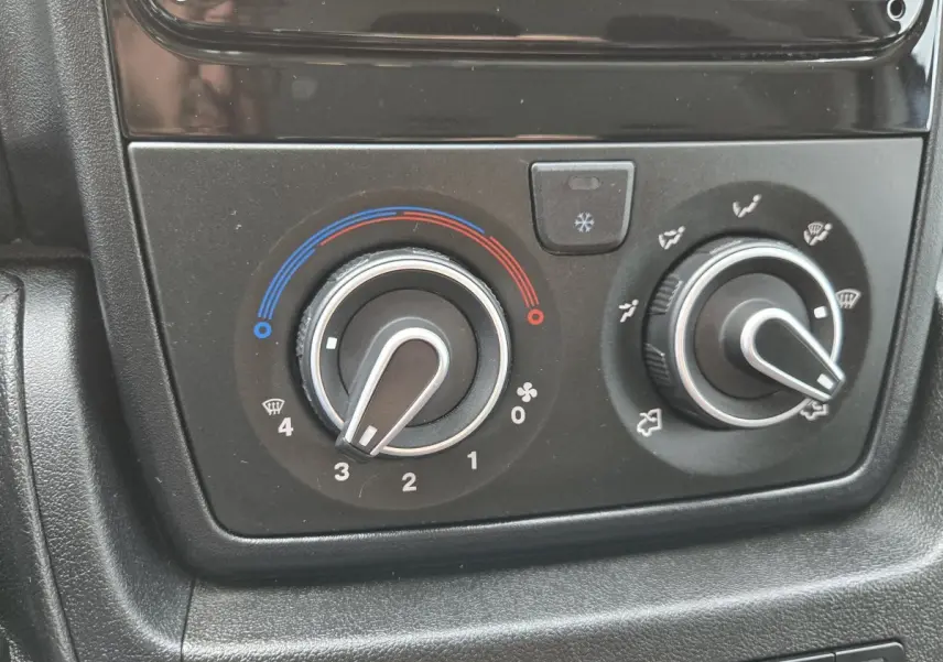 Gros plan sur les commandes de climatisation du Fiat Ducato Fourgon blanc, boutons de réglage température et ventilation.