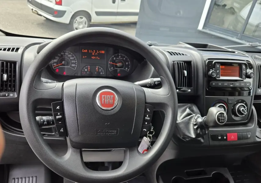 Vue intérieure centrée sur le volant noir FIAT et le tableau de bord du fourgon blanc FIAT Ducato 2023.
