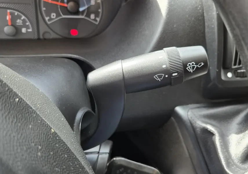 Gros plan sur la manette d’essuie-glace du tableau de bord du Fiat Ducato Fourgon blanc, intérieur noir.