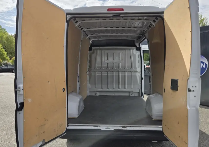 Vue arrière du FIAT Ducato Fourgon blanc 2023 avec portes ouvertes montrant l’intérieur vide et cloison pleine.