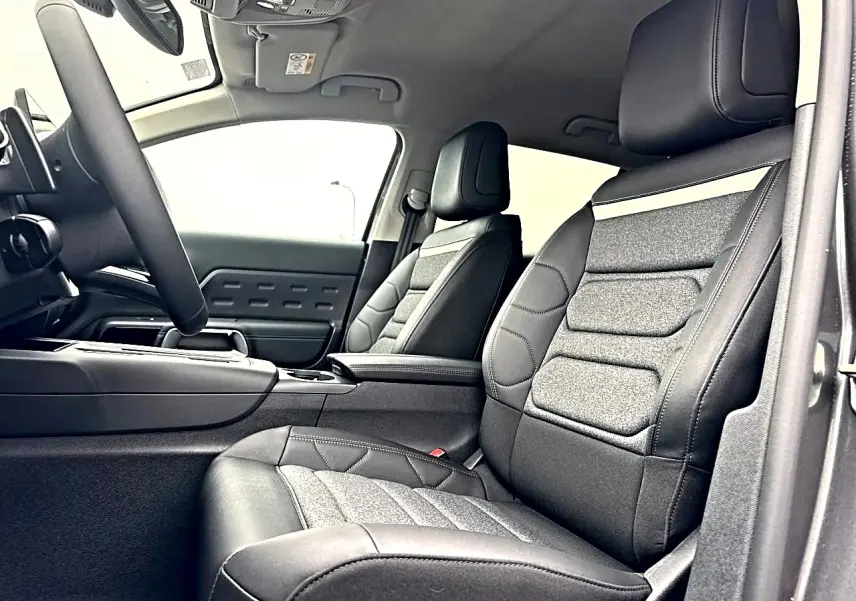Vue intérieure côté conducteur du Citroën C5 Aircross 2025, sièges en cuir et tissu gris avec accoudoir central.