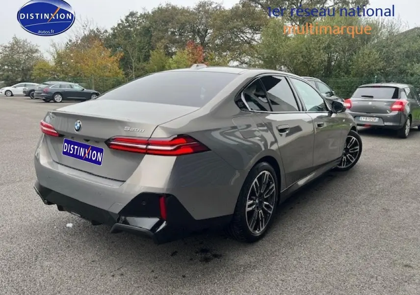 BMW Série 5 gris vue 3/4 arrière droit, avec jantes sport et feux arrière LED distinctifs.