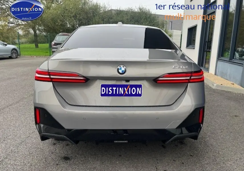 Vue arrière d'une BMW Série 5 gris métallisé (520da M Sport) avec feux LED et diffuseur noir brillant.