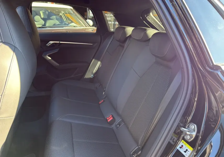 Vue côté gauche des sièges arrière en cuir tissu noirs de l'Audi A3 TFSI 150 Hybrid S-Line 2025 avec portière ouverte.