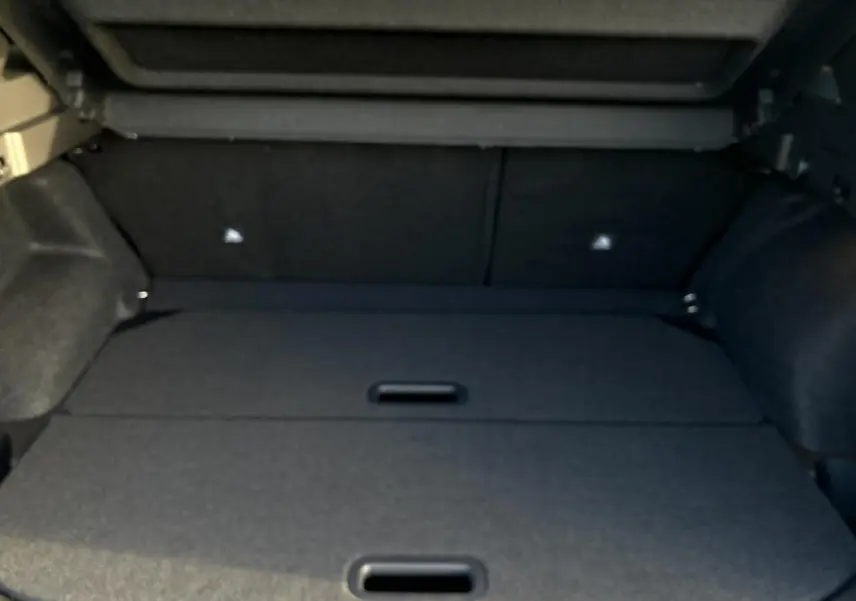 Coffre ouvert du Nissan Qashqai III noir, vue intérieure montrant le plancher de coffre modulable et les côtés tapissés.