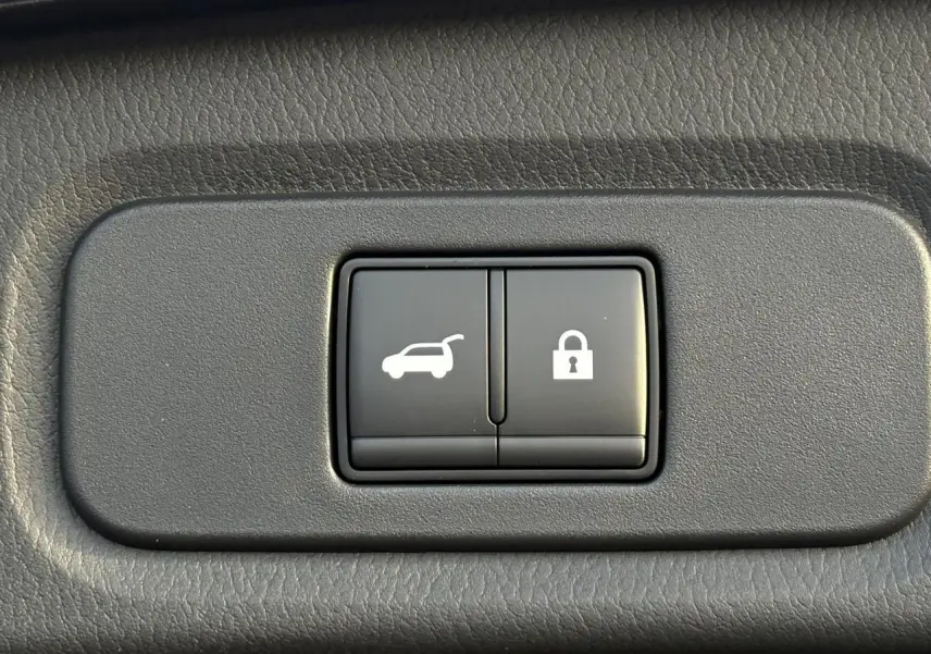 Gros plan sur les boutons d'ouverture du hayon et de verrouillage dans l'habitacle du Nissan Qashqai noir 2025.