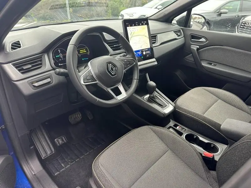 Vue intérieure côté conducteur du Renault Captur 2025 bleu Iron, avec volant multifonction et écran tactile vertical.
