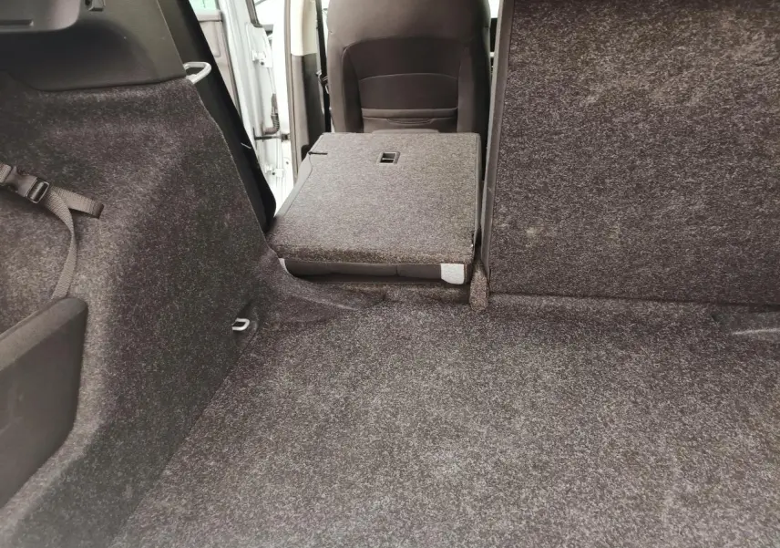 Vue intérieure du coffre du Skoda Kamiq 2025 avec banquette arrière rabattue côté gauche, revêtement gris foncé.