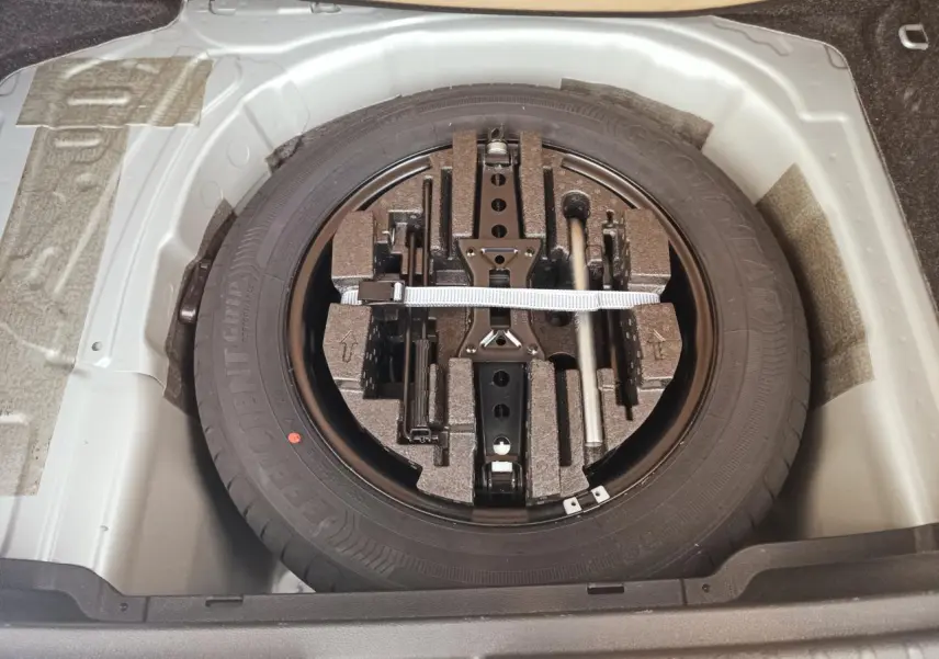 Vue plongeante sur la roue de secours et son kit d'outils dans le coffre d'une Skoda Kamiq 2025.