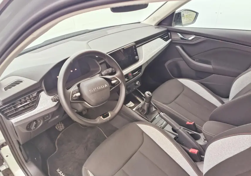 Intérieur de la Skoda Kamiq 2025 vu côté conducteur, sièges bicolores noirs et gris, volant multifonctions et boîte manuelle.