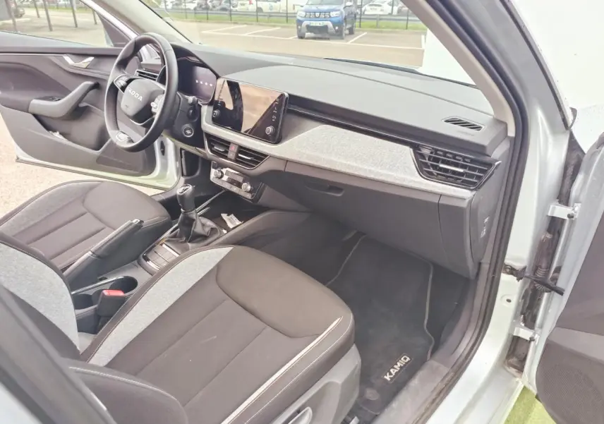 Intérieur avant droit d’une Skoda Kamiq 2025 gris argent avec tableau de bord moderne et boîte manuelle.