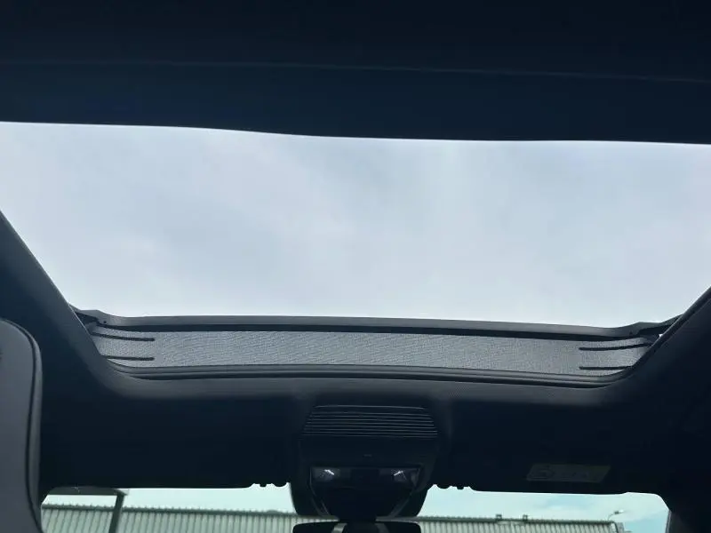 Toit ouvrant panoramique ouvert vu de l'intérieur du CUPRA Formentor noir Minuit métallisé, ciel nuageux en arrière-plan.