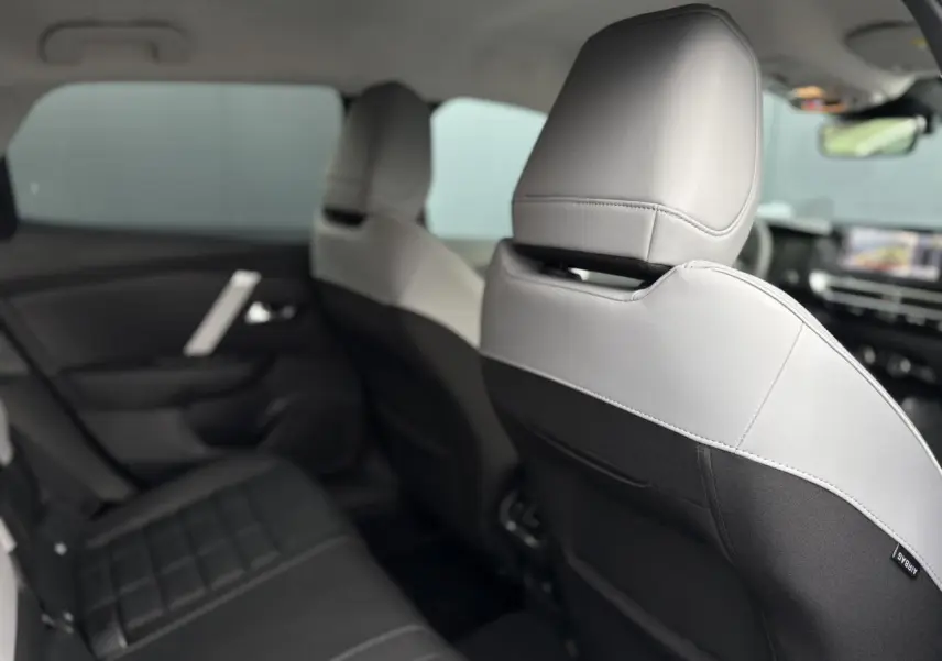 Vue intérieure arrière montrant les sièges bicolores gris clair et noir de la Citroën C4 Hybrid 2025.