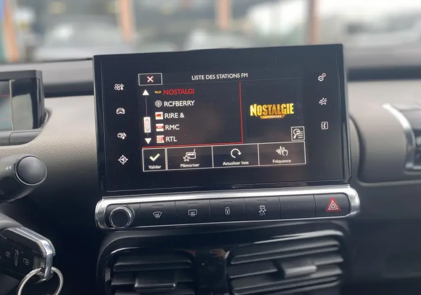 Vue rapprochée de l’écran tactile central du tableau de bord de la Citroën C4 Cactus 2015, affichant la liste des stations FM.
