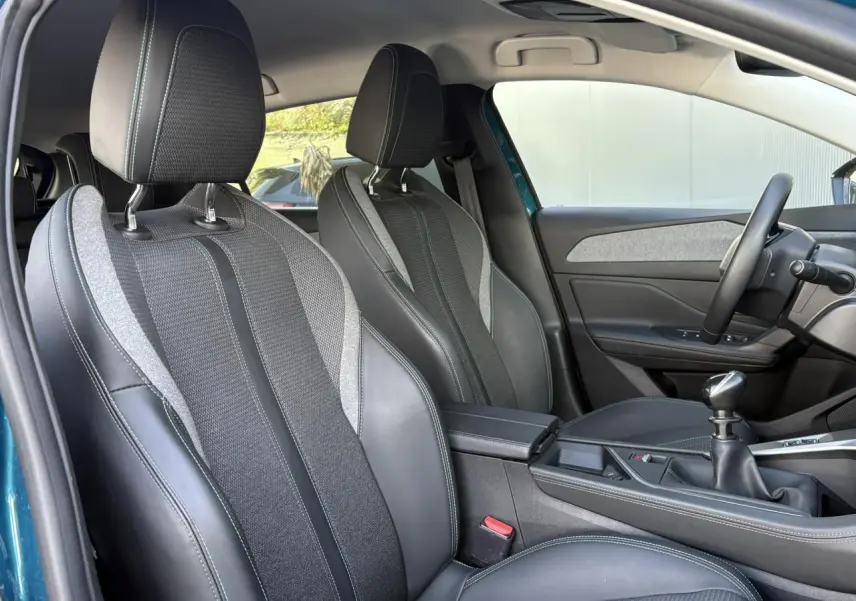 Vue intérieure côté conducteur de la Peugeot 308 Bleu Obsession, montrant sièges TEP/tissu et levier de vitesses manuel.