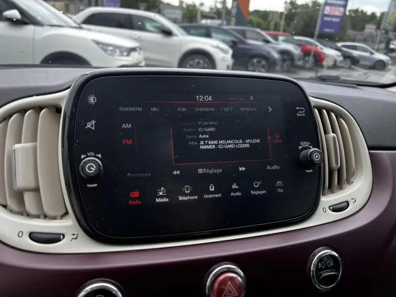 Tableau de bord de Fiat 500C 2020 avec écran tactile central allumé, entouré d'aérateurs beige et garniture bordeaux.